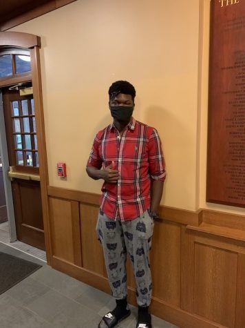 Iheukwumere Marcus 22 wears a casual outfit featuring a flannel, pajama pants and slides.