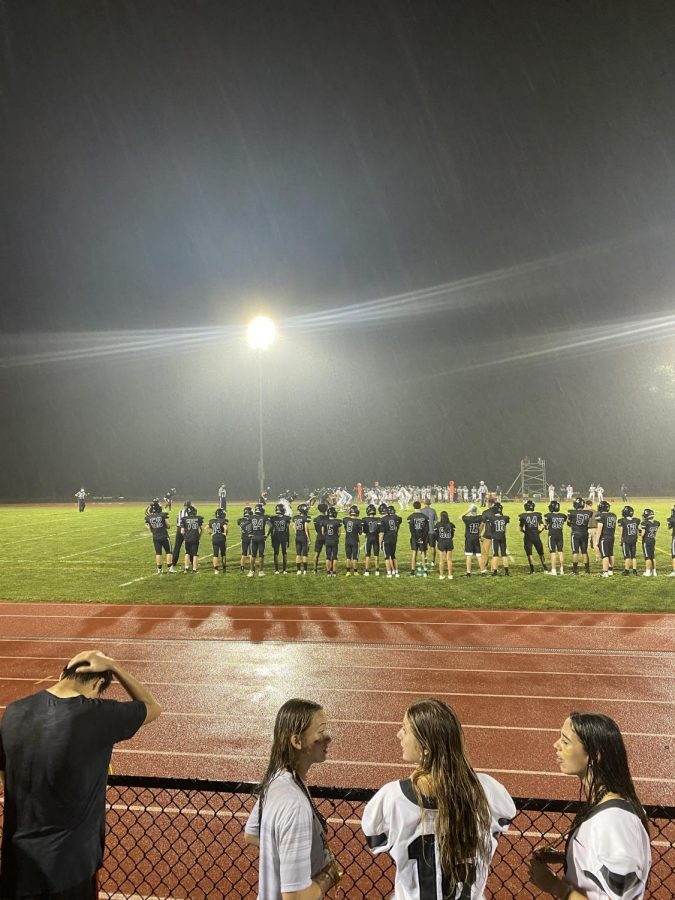 Shortly after crowds gathered for the football game, it started to rain. The chorus was able to sing the national anthem before it began raining.