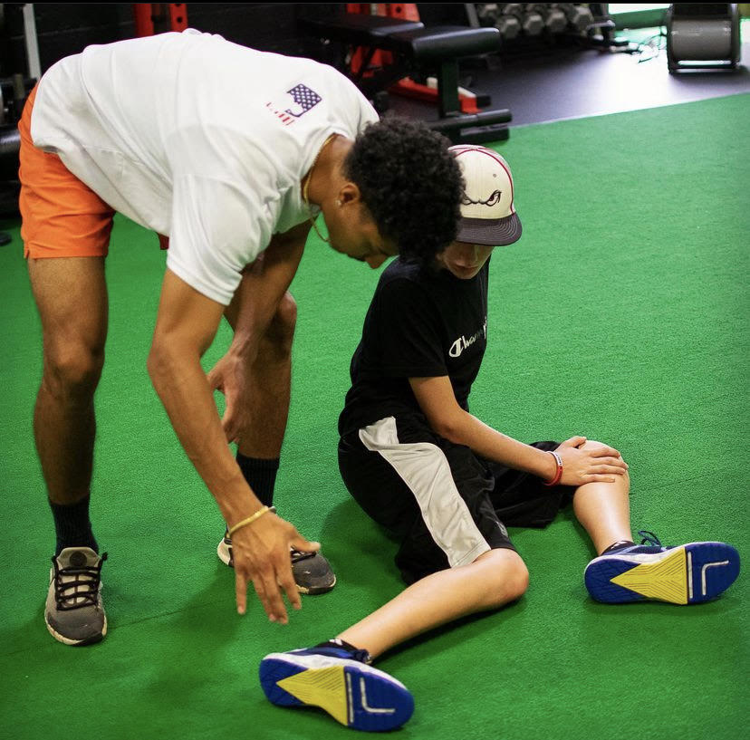 Coach Edwin is helping a young baseball  player before he starts practice. He spends some of his time working at GameOn13 which is a baseball and softball facility located near Tarrytown.