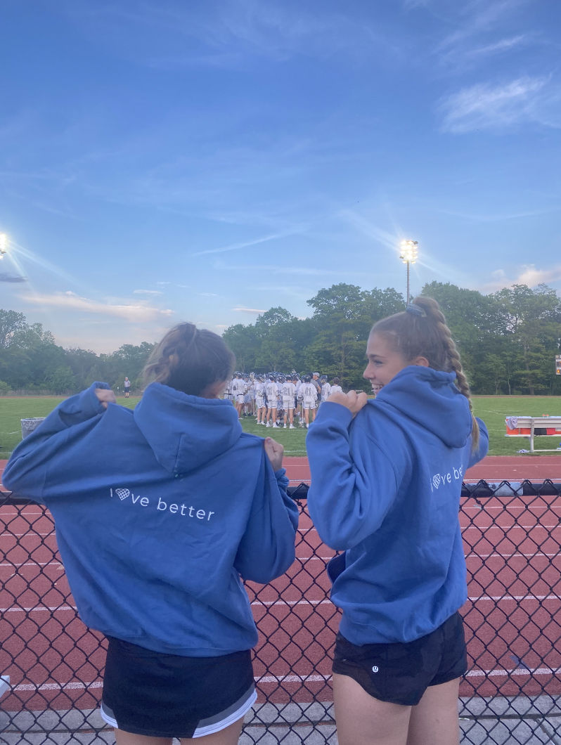 The girls lacrosse team made merch with all proceeds going to One Love. Juniors Annabel Hardart and Alex Schiller show off the new sweatshirts.