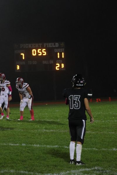 Senior cornerback Ike Shaw looks up at the Robert Pickert scoreboard late in a game versus Morristown Beard. The score helps to illuminate the field and help players understand what to do in different situations. 