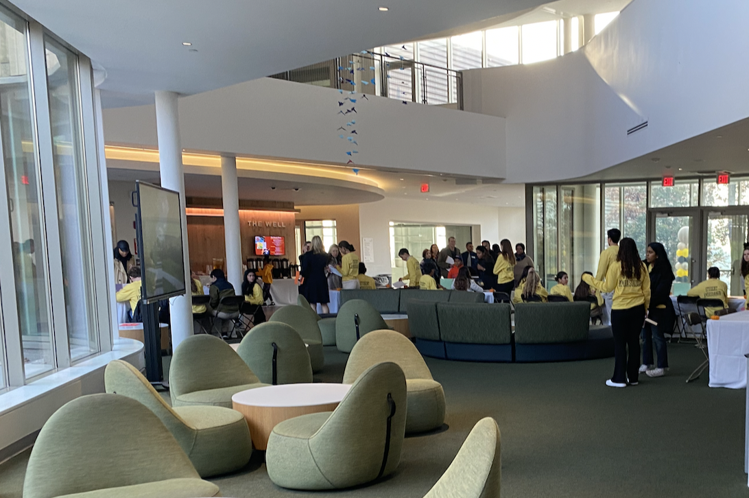 Student ambassadors, wearing yellow shirts, are gathered in the lobby of the Johnson Center. In the morning, they checked in prospective families and directed them to their demonstration lessons. Prior to families gathering in the Varsity Gym to hear initial remarks, the lobby was buzzing with families socializing and grabbing a bite to eat before the event.