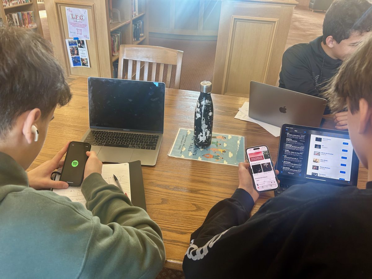 Two+students+studying+in+the+library+while+listening+to+music.+Here%2C+we+can+see+the+contrast+in+style+between+Spotify%2C+on+the+left%2C+and+Apple+Music%2C+on+the+right.+The+apps+are+different+colors%2C+and+also+have+different+fonts.