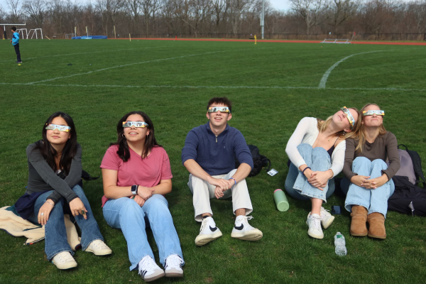 Seniors gather on Pickert Field to look up at the solar eclipse and experience the phenomenon together. They are wearing ISO-certified solar viewing glasses provided by Hackley.