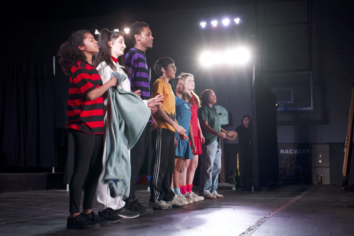 Cast members Cassandra Stand, Lilly Rosenthal, Asher Navas, Alex Booth, Arya Gauba, Ava Cronin, and Mikayla stand together for the plays finale! Voices blend together as their songs flows across the stage.