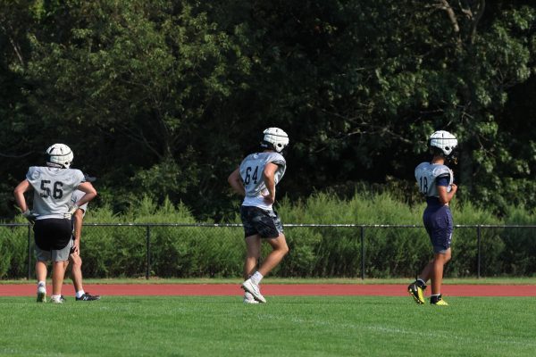 Senior captains Thomas O'Brien and Sam Suniewick and freshman Cassius Evans-Thompson wear guardian caps during a practice on Pickert Field. Although all offensive and defensive linemen wear the headgear during practice, they do not wear them during games.