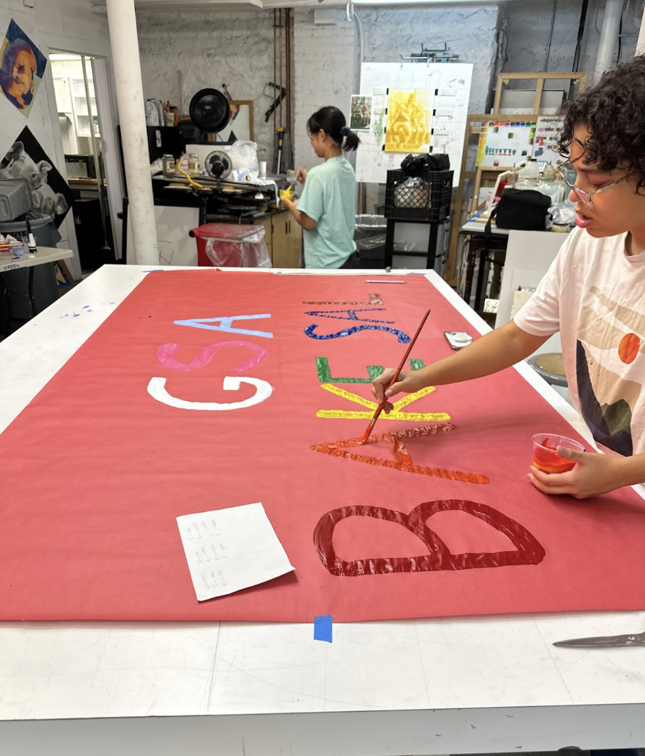 Junior Ari Spiegel is seen preparing for the GSA club bake sale by painting a vibrant sign that will attract buyers for the sale during a club meeting. In addition to raising money Ari hopes that this bake sale will help our community continue to foster  " a safe space for queer people," Ari said. 