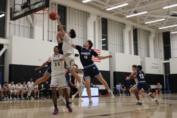 Sophomore Alex Nuzum goes up for a layup in an intense game against their rival, Poly Prep. The Boys' Varsity Basketball team had a tight game, ending in a 67-58 loss.