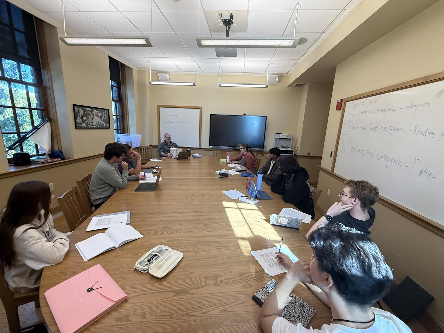 During a round table discussion, students listen to Mr. Fitzpatrick asking his guiding questions. On the white board are bullet points discussing different types of "good" with examples in every day life. "Each cycle there is a new reading, and in class we discuss it together and come up with our ideas and main takeaways," said Lara McComiskey.