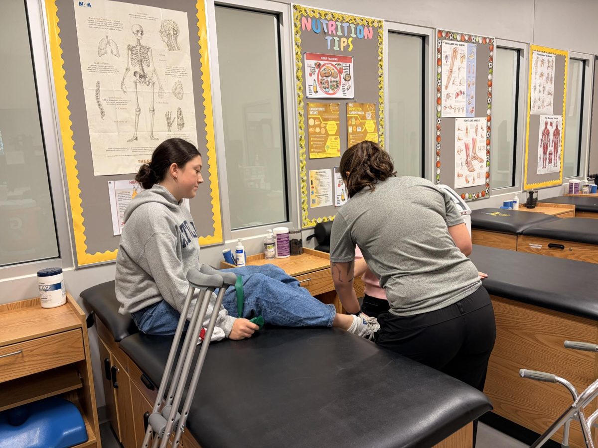 Whitney helps eighth grader Connelly Franklin try to figure out what is bothering her in her foot. Connelly's younger sister, Charlie is also there, who has her own injury she is recovering from. 