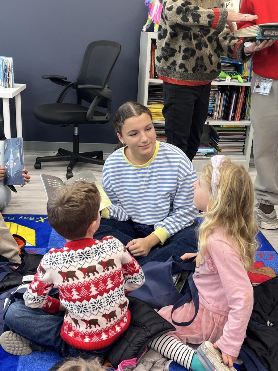 Sophomore Isa Llorca-Luth reads aloud to kindergartners at the 914 cares program. Kindergarten literacy  is just one of the many activities that the social impact through service leadership class does, with bake sales, drives, and Diller hall awareness presentations on pressing society issues. 
Photo courtesy of Ms. Swan