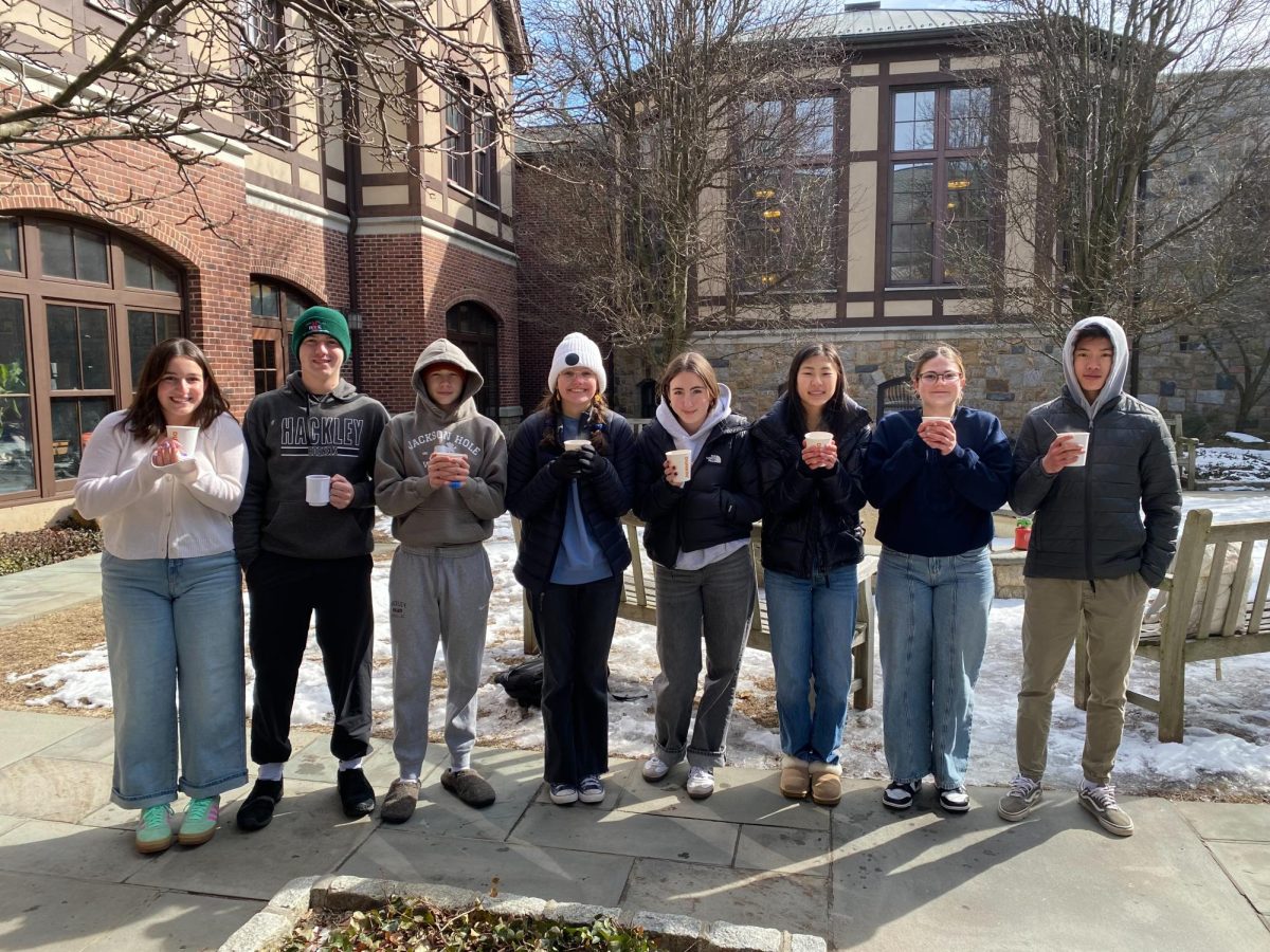 Hackley's campus is pictured here, now in January. The National Parks class of 2024-2025 is shown here, during their smores and hot chocolate event. Looking in the background, there is snow on the ground, and the students are dressed warmly, in jackets and hats, while most of them still look cold.